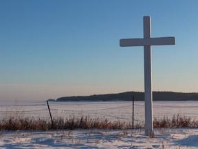 A cross outside the Nativity of the Blessed Virgin Roman Catholic Church overlooks the frozen Lake Athabasca in Fort Chipewyan, Alta. in this December 2014 file photo. Vincent McDermott/Fort McMurray Today/QMI Agency