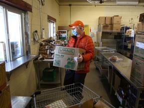 John Waddell carries a box of food to a window at the Partners in Mission Food Bank, where a courier waits to deliver it to a client in Kingston on Monday, April 18.