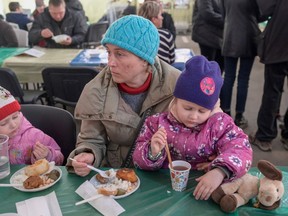 A woman and children eat after their arrival at a displaced persons' hub in Zaporizhzhia, some 200 kilometers northwest of Mariupol, Ukraine, on Tuesday.  BULENT KILIC/Getty Images