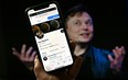 In this photo illustration, a phone screen displays the Twitter account of Elon Musk with a photo of him shown in the background, on April 14, 2022, in Washington, DC.