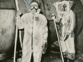 Two workers wearing protective clothing clean up after the NRX incident in 1952. Courtesy of Toronto Public Library. Public domain photo