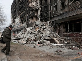 A local resident walks near an apartment building destroyed during Ukraine-Russia conflict in the besieged southern port city of Mariupol, Ukraine, on March 31, 2022. Alexander Ermochenko/Reuters