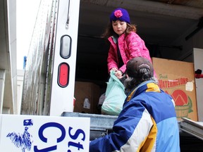 Sisters Ilianna Mestancik, 6, and Maia Mestancik, 8, collect donations from Inn of the Good Shepherd volunteer Bill Chapple outside the Real Canadian Superstore during the Cyclone Aid food drive on Saturday, April 9, 2022 in Sarnia, Ont.  Terry Bridge/Sarnia Observer/Postmedia Network