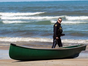 A Lambton OPP officer inspects a canoe that capsized on Wednesday, April 20, 2022 in Ipperwash Beach, Ont.  Terry Bridge/Sarnia Observer/Postmedia Network