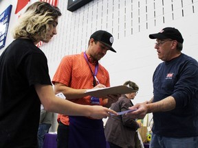 From left, volunteers Joseph Cleveland and Nick Stokley sell a raffle ticket to Mike Arnold, all Sarnia residents, during the Big Brothers Big Sisters of Sarnia-Lambton's Spring Show and Sale inside Lambton College's gym on Saturday, April 30, 2022 in Sarnia, Ont .  Terry Bridge/Sarnia Observer/Postmedia Network