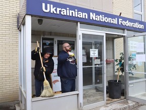 Workers from Cosmos Glass Corporation prepare to install a new pane of glass at the Ukrainian National Federation hall on Frood Road on Thursday. The window was smashed on Tuesday night.