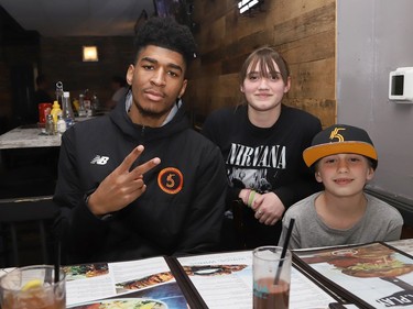 Tyrell Gumbs-Frater, of the Sudbury Five, meets with fans Alexis Schilkie, 13, and her brother, Jared, 8, at a fundraiser for the Sudbury Food Bank at Overtime Bar and Grill in Sudbury, Ont. on Friday April 29, 2022. Sudbury Five teammates were on hand to meet fans and serve up food with 10 per cent of food sales going to the food bank. John Lappa/Sudbury Star/Postmedia Network
