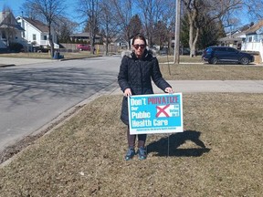 Sarnia-Lambton Health Coalition co-chair June Weiss poses with a lawn sign. The Ontario Health Coalition chapter is trying to make healthcare spending a provincial election issue locally. Submitted