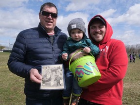 Two-year-old Louie Vandepoele enjoyed Saturday's Tillsonburg Kinsmen Easter Egg Hunt, much like his dad Devin (on the right) did when he was two, assisted by Louie's grandfather Marc Vandepoele. Marc is holding the photo of two-year-old Devin he kept as a momento. (Chris Abbott/Norfolk and Tillsonburg News)