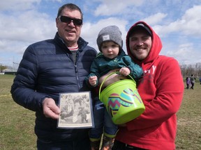 Two-year-old Louie Vandepoele enjoyed Saturday's Tillsonburg Kinsmen Easter Egg Hunt, much like his dad Devin (on the right) did when he was two, assisted by Louie's grandfather Marc Vandepoele. Marc is holding the photo of two-year-old Devin he kept as a momento. (Chris Abbott/Norfolk and Tillsonburg News)