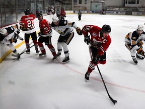 Tyler Mahan held the puck for the Wolverines while Saints player Jaden Senkoe looked to take it during a January game, where the Wolverines won 2–1.