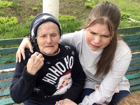 An elderly woman weeping over the loss of her son last week from a bombing near Kyiv is comforted by a teenage girl whose father is at war.  ROBERT PEACE
