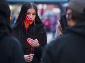 A MMIWG vigil attendee holds a flame as the sun beings to set on Belleville's Market Square Thursday. ALEX FILIPE