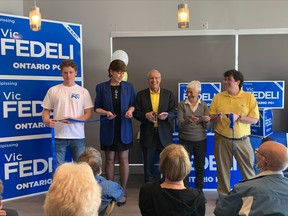 Vic Fedeli cuts the ribbon at his campaign office for the June 2 provincial election Friday morning. His 89-year-old mother, Lena, and wife, Patty, joined him on stage in front of family, friends and supporters.