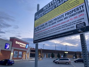 Signs outside the Shoppers Drug Mart on Elm Street warn drivers that unauthorized vehicles risk being immobilized with a booting device.