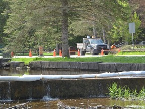 A berm runs across the water channel at Harrison Park on Tuesday, May 17, 2022, after a small diesel fuel spill in a parking lot at the park on Monday. A parking lot at the park has been closed off while the spill is cleaned up and monitoring takes place.