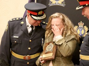 Chief Hugh Stevenson and Deputy Chief Robert MacLachlan comfort an emotional Wendy Gutcher after she received a plaque recognizing her efforts with Sault Ste. Marie Helping Hands on Tuesday, May 17, 2022 in Sault Ste. Marie, Ont. (BRIAN KELLY/THE SAULT STAR/POSTMEDIA NETWORK)