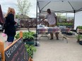 Donovan Daniel from Earth and Soul Farm in Corbeil helps customers Saturday at the North Bay Farmers' Market. Daniel said the unseasonal warm weather kick-started the growing season into high gear.