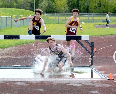 Sam Koistinen, of Timiskaming District Secondary School, grimaces as he lands in the water, while École secondaire catholique Thériault teammates Nathan Lemire, left, and Justin Kim approach the hazard during the Open Male 2,000-Metre Steeplechase at the 2022 NEOAA Track & Field Championships at Timmins Regional Athletics and Soccer Complex on Wednesday. Lemire won the event, while Koistinen was second and Kim third. THOMAS PERRY/THE DAILY PRESS