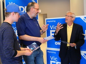 Peter Bremermann, left, and William Ferguson discuss some of the new campaign literature with Progressive Conservative candidate Vic Fedeli.