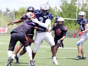 Sudbury Junior Spartans running back Zidaine Allen (3) gets wrapped up by a couple of Peel Panthers while running the ball during Ontario Summer Football League action at James Jerome Sports Complex in Sudbury, Ontario on Saturday, May 28, 2022.