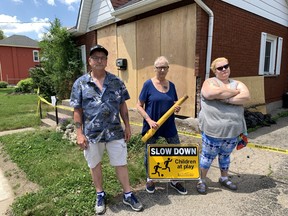 Neighbours Mark Woods, left, Jenney Vinnick-Gould and Oliviea Allison stand in front of Vinnick-Gould's Grand River Avenue home that a vehicle crashed into on Victoria Day, rocking the home off its foundation and traumatizing the owners.