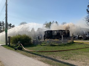 A Saugeen First Nation Fire Department crew poured water on a smouldering house fire on Highway 21 at Cameron Dr. in Saugeen First Nation May 10. The cause of the fire is under investigation. There were no injuries but a family cat was missing at press time. [Frances Learment]