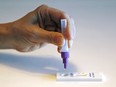 A person squeezes a drop of testing solution into a COVID-19 rapid antigen testing device.