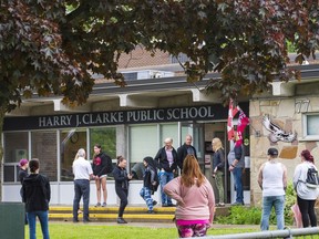 Parents wait on the front lawn of Harry J. Clarke Public School to pick up their children on Friday after hold-and-secure measures were lifted for a number of east end schools.