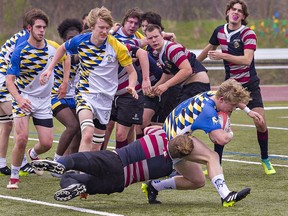 Owen Cherewka of the Assumption Lions goes along for the ride as he latches onto BCI Mustangs ball carrier Evan Wilson during a high school boys rugby match at Kiwanis Field in Brantford on Tuesday May 3, 2022.