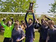 Assumption Lions captan Damani James hoists the trophy as the team celebrates their 2-1 win over the St. John's Eagles to claim the Athletic Association of Brant, Haldimand and Norfolk high school boys soccer championship.