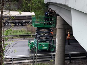 OPP measure the height of the North Park Street bridge over Highway 403 where it was struck Wednesday by a flatbed truck carrying a construction vehicle.