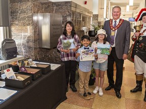 Young Brantford artists (from left) Kianna Kara Angel Hess, age 13; Yashveer Kayal, 7; and ten-year-old Sophia Lee are joined by Brantford mayor Kevin Davis and town crier David McKee as their artwork, along with other mementoes were to be placed in a time capsule at City Hall on Tuesday May 31, 2022. Brian Thompson/Brantford Expositor/Postmedia Network
