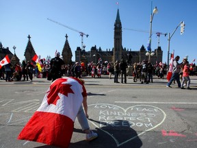 A woman draws with chalk on Wellington Street in front of Parliament Hill, during demonstrations in Ottawa on Saturday.