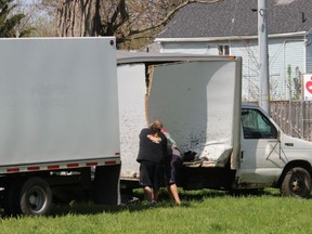 Two people work on prying open the box of a cube van that was damaged when the vehicle was struck by a freight train at railway crossing on Colborne Street in Chatham Tuesday afternoon.  Ellwood Shreve/Chatham Daily News
