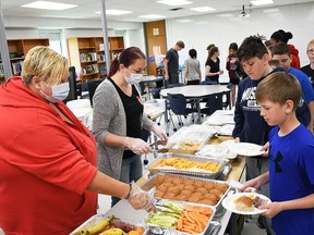 Tricia Charles and Elisha Banks, volunteers with We Are One, serve out food to students at St. Elizabeth Catholic School for the final day of a two-week nutritious meal pilot program on May 13.