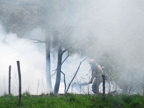 A Kingston firefighter clears debris at the scene of a fire at Lemoine Point Farm on Friday.