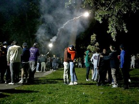 A couple seen kissing as someone launches a firework over the crowd in Victoria Park as thousands of students gather at an unsanctioned Queen's University Homecoming party in violation of restrictions in place to limit the spread of COVID-19 on Oct. 17, 2021.