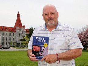 Former correctional officer Dave Woodhouse outside the property of Collins Bay Institution on Bath Road with his book, "West Yard," on May 18.