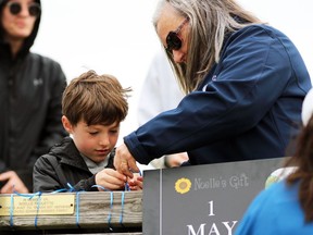 Zachary Paquette and Lynn Paquette tie blue ribbons to Noelle Paquette's memorial bench in memory of Marg Stewart on Sunday, May 1, 2022 in Point Edward, Ont.  Terry Bridge/Sarnia Observer/Postmedia Network