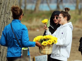 Anita Trusler hands out sunflowers to Alex Stewart and MacKinleigh Stewart prior to a memorial walk for their mother Marg Stewart on Sunday, May 1, 2022 in Point Edward, Ont.  Terry Bridge/Sarnia Observer/Postmedia Network