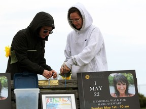 Alex Stewart, left, and MacKinleigh Stewart tie blue ribbons to Noelle Paquette's memorial bench in memory of their mother Marg Stewart on Sunday, May 1, 2022 in Point Edward, Ont.  Terry Bridge/Sarnia Observer/Postmedia Network