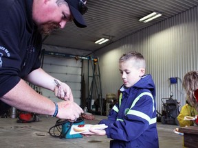 Lucas Corsaut, 8, from Sarnia is handed a burger by Brian Moore during the Sarnia Street Cruisers event at Preferred Towing on Sunday, May 22, 2022 in Sarnia, Ont.  Terry Bridge/Sarnia Observer/Postmedia Network