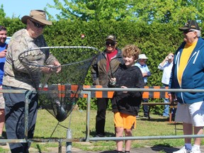 Paul Heckley, with the Bluewater Anglers, nets a fish Bentley Dolan, 8, of Sarnia, caught Saturday in the pond at the hatchery in Point Edward during the anglers' annual Kids' Training Day.  Volunteer Lloyd Blonding, right, helped Bentley land the rainbow trout.