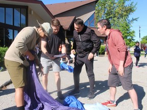 Members of team TMRRW, from left, Jason Nguyen, Josh McDonald, Lewis Menelaws, and Shawn Vogt assemble a bedroll during a Girl Guides-organized competition at Grace United Church in Sarnia during Saturday's Race to Erase community event.