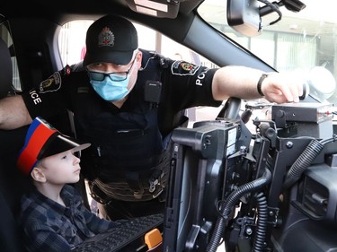 Four-year-old Jackson Twain sits in a police vehicle while Sgt. Matt Hall, of the Greater Sudbury Police, shows him the gadgets in the vehicle in Sudbury, Ont. on Wednesday May 11, 2022. John Lappa/Sudbury Star/Postmedia Network