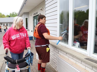 Raphael Delparte, 13, cleans a window as resident Mimi Renaud looks on at The Walford Sudbury on Thursday May 19, 2022. Grade 8 students from Ecole St-Denis visited the retirement home in Sudbury, Ont. to put their Pay it Forwardproject into practice by giving back to the local community and seniors. During their visit, students cleaned windows, doors and siding, swept the grounds, repaired flower beds, painted benches and cleaned up the property. John Lappa/Sudbury Star/Postmedia Network