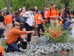 Darrell Grenier throws flowers into the water at a ceremony at Ramsey Lake in Sudbury, Ont. on Friday May 27, 2022, in memory of Indigenous children who never came home, in particular, the original 215 children in Kamloops, B.C. John Lappa/Sudbury Star/Postmedia Network
