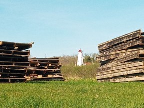 Panels of a former Port Burwell harbourside boardwalk are piled in a field, framing the landmark Port Burwell lighthouse.Eric Bunnell