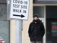 A person stands near a sign for a COVID-19 Test site in Winnipeg. Chris Procaylo/Winnipeg Sun